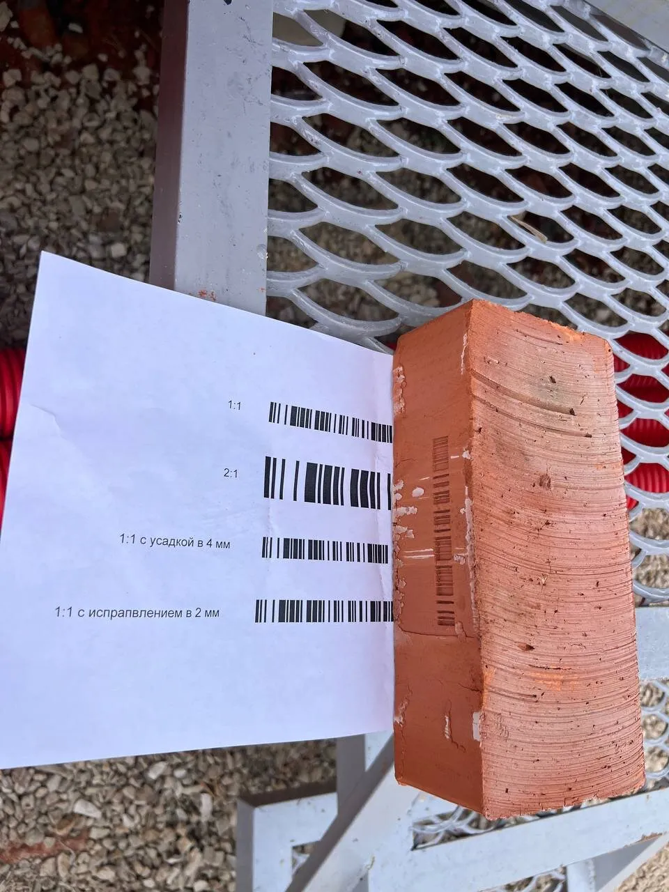 Sheet of Code128 references at different scales next to a brick